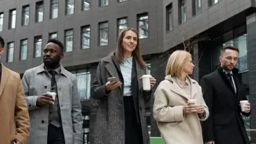 six people walking together in the business district, with a cup in hand