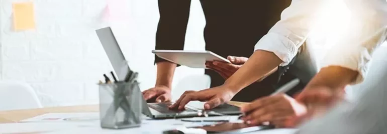 People collaborating around a table with laptops and tablets.