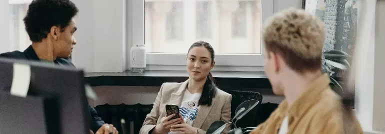 Three people having a discussion in a modern office setting.